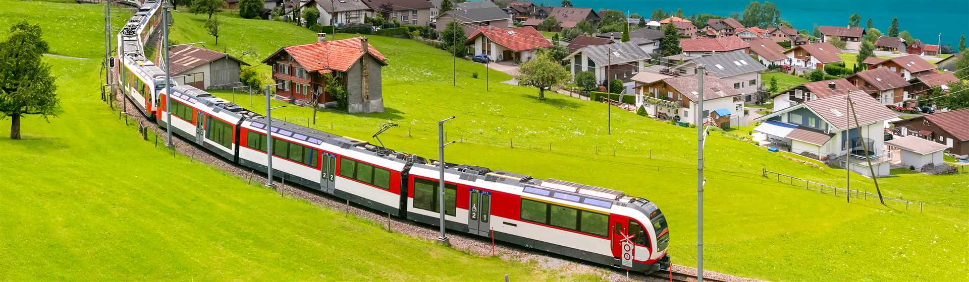 Modern red and white train passing Lake Lungern with alpine scenery