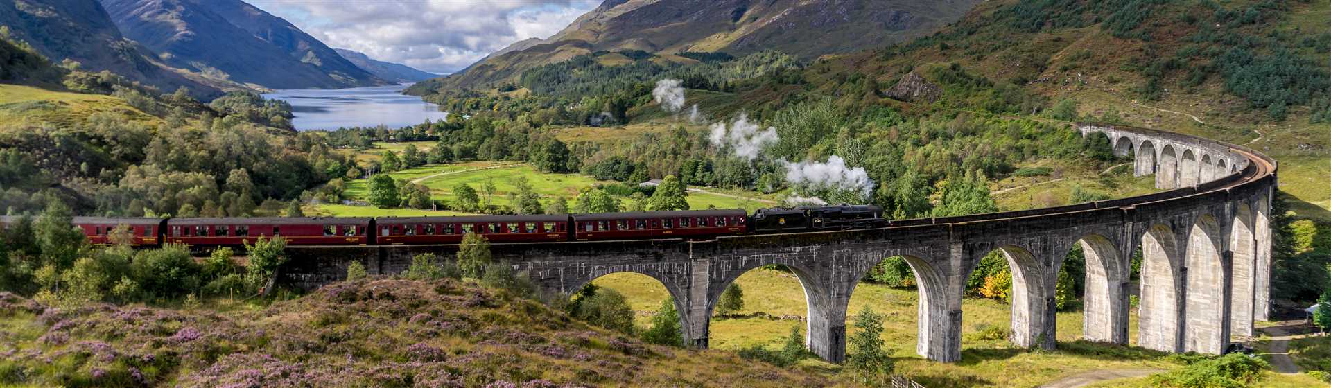 Steam train crossing Glenfinnan Viaduct with Scottish Highlands scenery